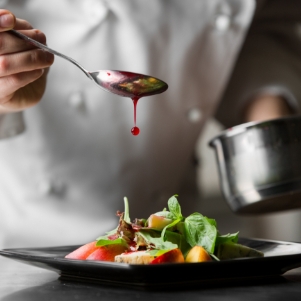 image of a salad preparation with chef in background representing end user